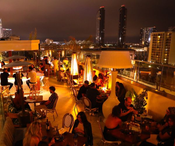 many people sitting on top of a roof top enjoying the night