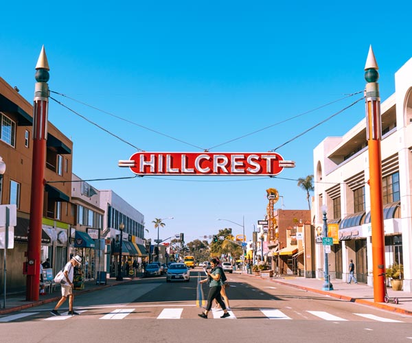 Hillcrest neighborhood sign above pedestrians crossing the street